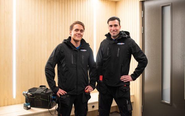 to elektrikere fra norgeseliten står utenfor en boligdør